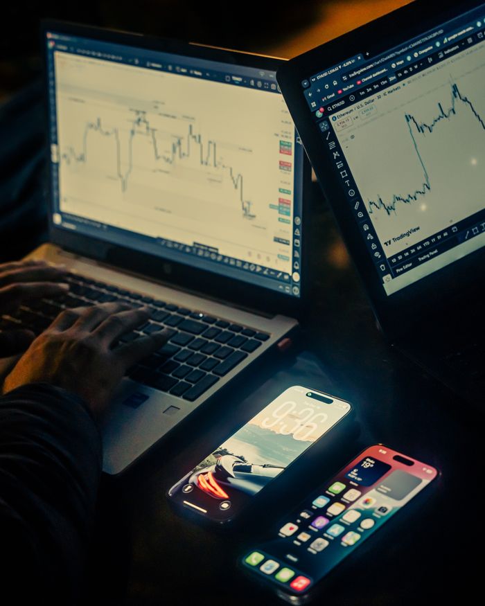 Crafting Captivating Headlines: Your awesome post title goes here A trading workspace with laptops displaying charts and smartphones, set in a low light environment, Dhaka.